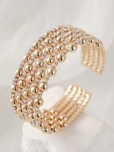 Macro detail of multilayer gold-plated bracelet with rows of rhinestones and beads