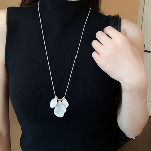 Close-up of a silver petal pendant necklace on a black turtleneck sweater