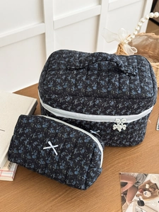 Detailed view of quilted navy floral cosmetic bag set with ribbon bow and metal charms