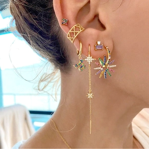 Close-up of golden sunflower and butterfly earrings with colorful zircons on ear