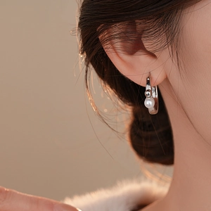 Gros plan d'une boucle d'oreille anneau argenté avec perle sur un mannequin