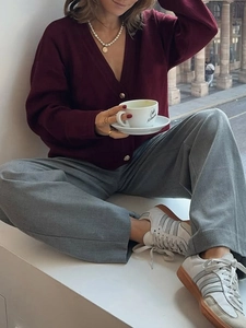 Close-up of casual burgundy knitted cardigan paired with grey wide-leg trousers and sneakers