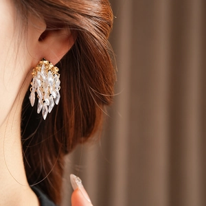 Gros plan de boucles d'oreilles dorées à pampilles et gouttes de cristal sur un mannequin