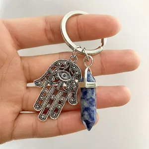 Detail of Hamsa Hand and hex crystal pendant held in hand for size display