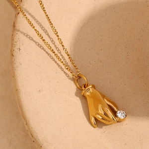 Elegant 18K gold-plated hand pendant necklace holding a clear white crystal stone