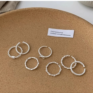Set of 7 silver minimalist adjustable rings featuring twist, chain, and bow designs