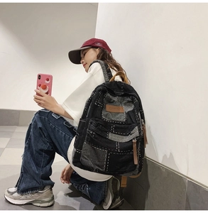 Detailed side view of a denim patchwork backpack on a model in an urban street setting