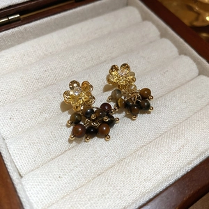 Dettaglio degli orecchini a fiore con nappe in occhio di tigre su scatola in velluto