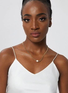 Detailed close-up of a minimalist gold chain necklace with a single white pearl pendant