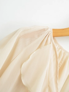 Detail of off-white layered blouse with textured chiffon fabric and pleated shoulders