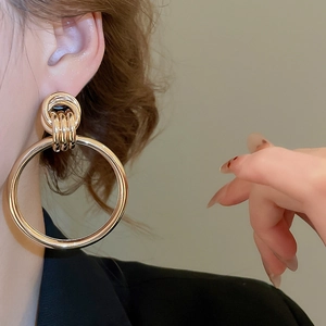 Detailansicht großer goldener geometrischer Creolen an einem Model mit elegantem Styling