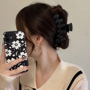 Pince à cheveux noire mate et créoles dorées portées par un mannequin de profil