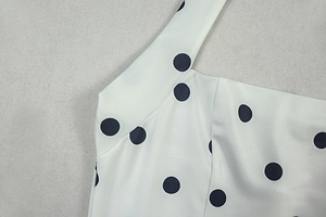 Detailed view of the neck strap stitching on a white and black polka dot A-line dress