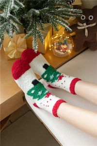 Détail de chaussettes de Noël en polaire corail avec talons rouges et sapins verts