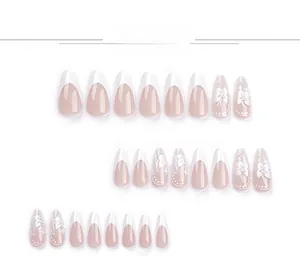 Macro shot of 3D white bow and pearl details on French-style nude pink press-on nails