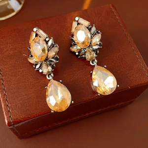 Close-up of vintage amber teardrop earrings with crystals on brown leather base