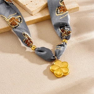 Detailed close-up of tiger print silk scarf chain necklace with gold flower pendant
