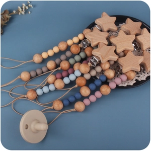 Silicone and beech wood star pacifier clips in various colors displayed on a blue tray