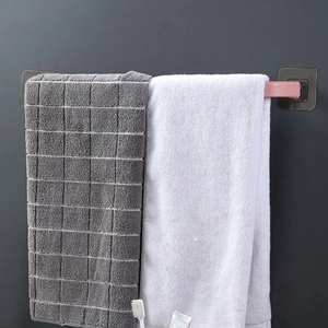 Pink wall-mounted towel rack with adhesive patch holding two towels in bathroom scene