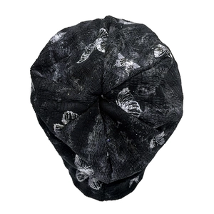 Close-up of black knit beanie with gray butterfly pattern on white background