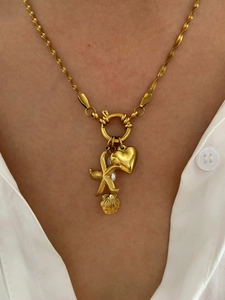 Detail of titanium steel necklace with starfish, heart, and pearl charms on a gold chain