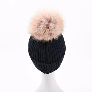 Berretto in maglia nera con paraorecchie e soffice pompon rosa su manichino bianco
