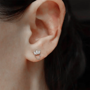 Macro shot of silver stud earring with three marquise-cut stones and thin chain tassel