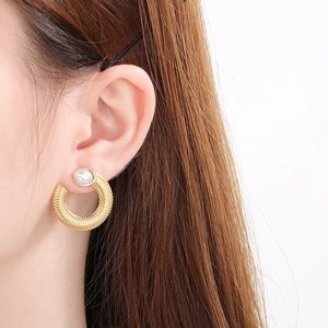 Macro view of French retro U-shape gold hoop earrings with spiral texture and white pearl
