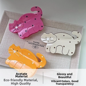 Detailed macro view of three cat-shaped acetate hair claws with polka dots in a tray