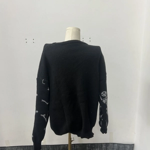 Detail of sleeve showing grey skull bone knit pattern on black crewneck sweater