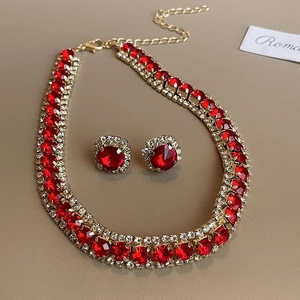 Macro view of vintage gold finish flower necklace and earrings set with red crystals