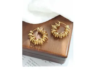Detail of gold spiral hoop earrings on a vintage jewelry box with soft fabric accents