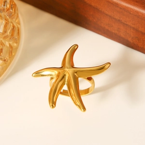 Close-up of polished gold starfish ring with intricate texture on a minimalist surface