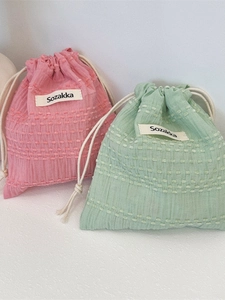 Pink and mint green drawstring storage bags with textured polka dots in a soft setup