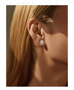 Macro shot of oval opal halo earring with sparkling zircon borders on model's ear