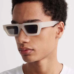 Close-up of stylish rectangular sunglasses with thick light grey frames on a model