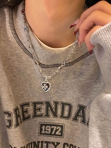 Macro detail of silver heart necklace featuring a cross pattern and colorful gemstones