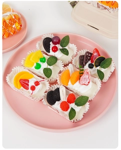 Close-up of assorted artificial fruit cupcakes in paper liners on a pink plate