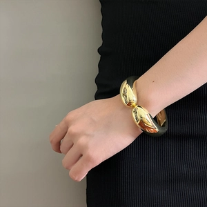 Detail of a minimalist gold layered irregular bracelet with black resin lining
