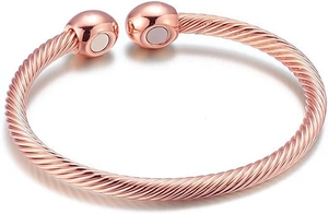 Macro detail of rose gold twisted cable cuff bracelet with magnetic round metal ends