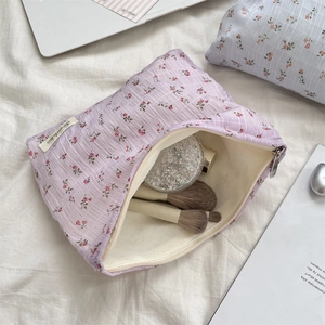 Détail de la trousse de toilette en toile à fleurs avec pinceaux et produits cosmétiques
