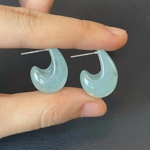 Boucles d'oreilles créoles en résine bleu d'eau avec tiges en argent à la main
