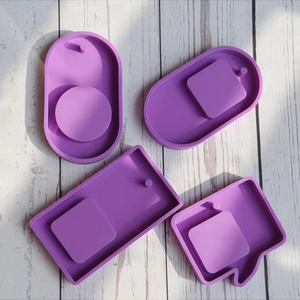 Detailed macro view of four purple silicone molds for DIY crafts on a white wood surface