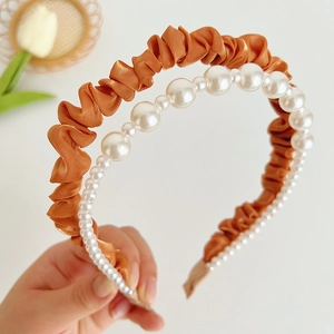 Detail of elegant caramel satin headband paired with a gradient white pearl strand