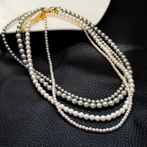 Lustrous white and grey pearl necklaces layered on black leather background