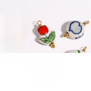 Close-up of hand-painted floral ceramic pendant with gold-plated loop and heart patterns