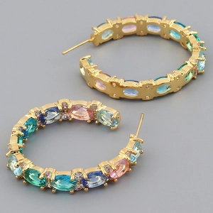 Detailed macro view of gold C-hoop earrings featuring vibrant multi-color oval gemstones