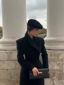 Détail du manteau en laine noire ajusté avec sac à main élégant doté d'un fermoir doré