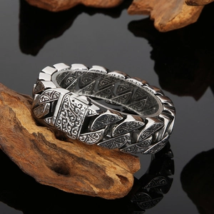 Detailed close-up of a silver cuban chain ring with intricate vintage floral carvings