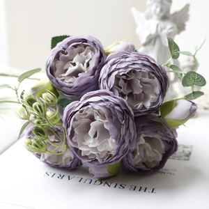 Detail of purple artificial peony bouquet with gradient petals and realistic green leaves